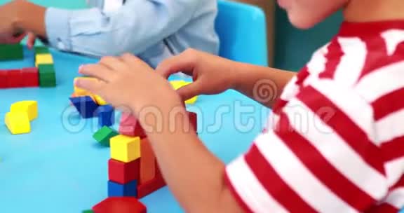 可爱的小男孩在桌子上玩积木视频的预览图