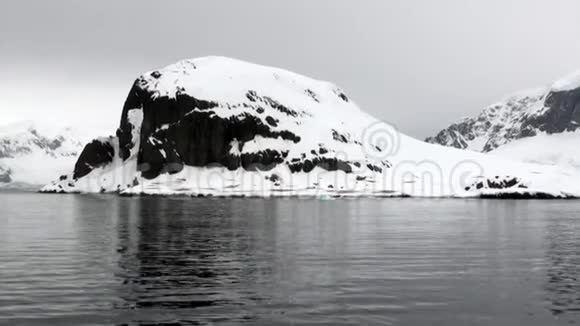 企鹅在雪的岩石海岸冰山和浮冰在南极洲的海洋视频的预览图