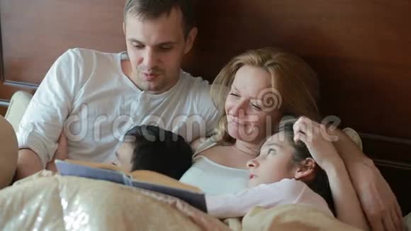 快乐的一家人在床上大声读一本书视频的预览图