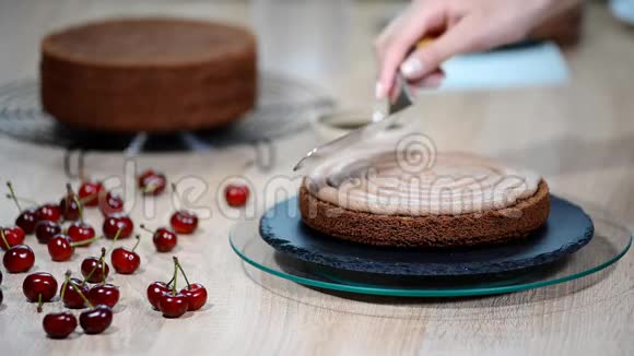 不可辨认的女性糕点厨师在厨房的开胃层蛋糕上挤压巧克力奶油视频的预览图