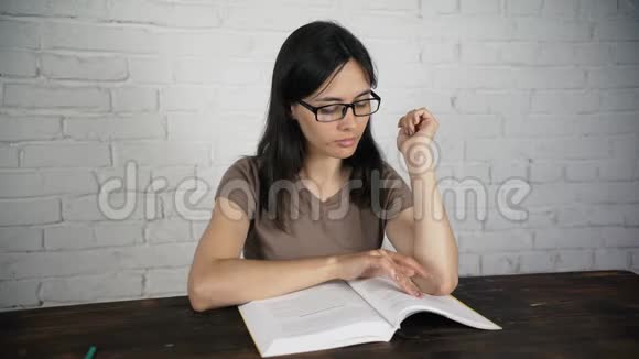 女孩坐在一张白色的桌子上戴着眼镜看着一本书日记视力不好视频的预览图