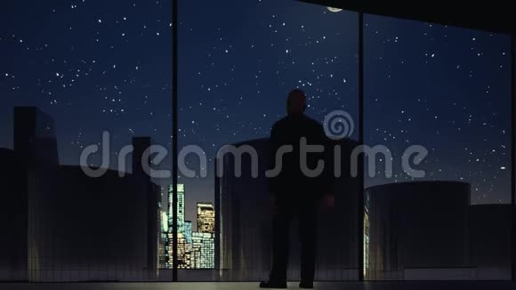 一个男人在办公室的窗户里看着晚上的录像视频的预览图
