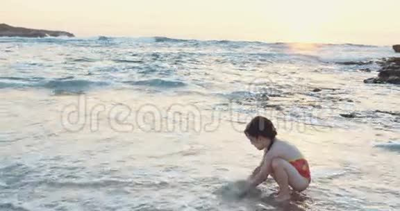 日落时分小女孩在海滩上玩海浪视频的预览图
