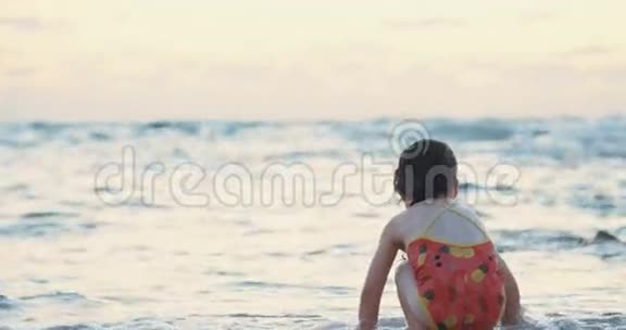 日落时分小女孩在海滩上玩海浪视频的预览图