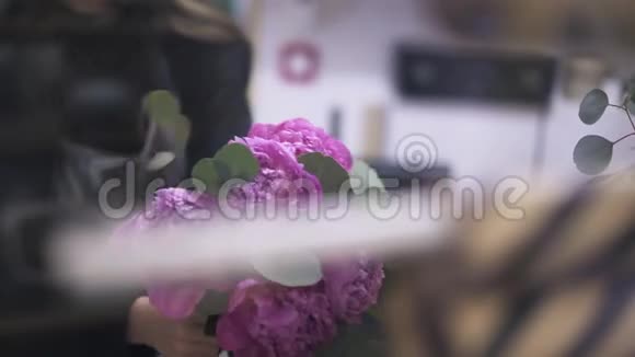 一位年轻的女花匠在商店里布置一束粉红色的花束视频的预览图