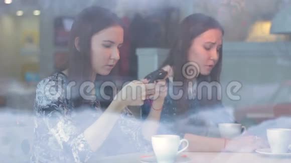 女青年与朋友交谈在咖啡馆里使用智能手机视频的预览图