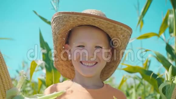 一个穿着草帽在玉米地里微笑的男孩的肖像视频的预览图
