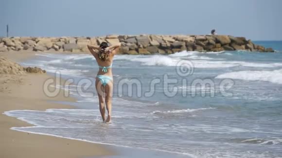 穿着泳衣的女孩在海边慢动作地奔跑视频的预览图