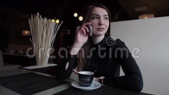 在咖啡馆里的漂亮女孩在打电话喝咖啡视频的预览图