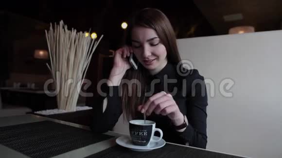 在咖啡馆里的漂亮女孩在打电话喝咖啡视频的预览图