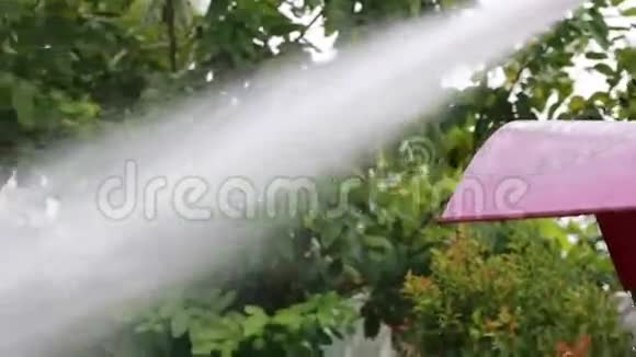 不明身份的亚洲工人用一个强大的软管喷雾器冲洗道路视频的预览图