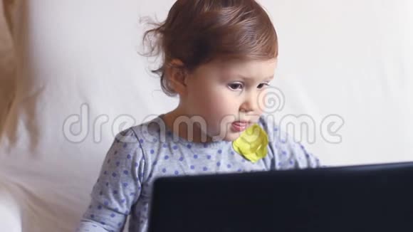 漂亮的女孩坐在笔记本电脑前学习上网视频的预览图