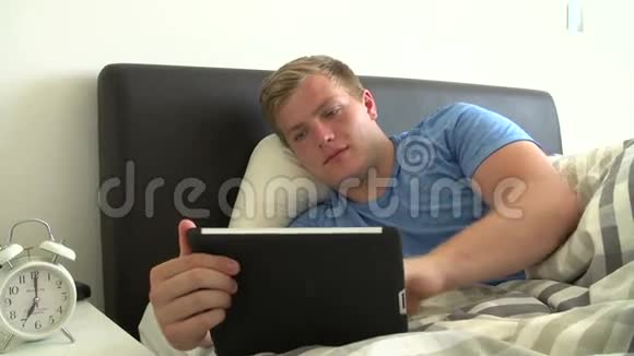 使用数码平板电脑躺在床上的青少年视频的预览图