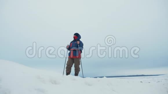 一个人背着背包背着跋涉的棍子在冬天的群山背景下美丽的日落山上的雪A视频的预览图