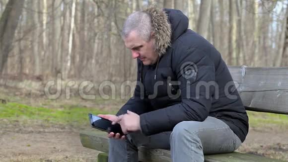 坐在长椅上用智能手机的沮丧男人视频的预览图