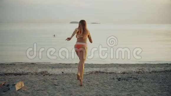 美丽的女孩在水上奔跑喷散了黄昏时分瘦小的女人在傍晚跑步视频的预览图