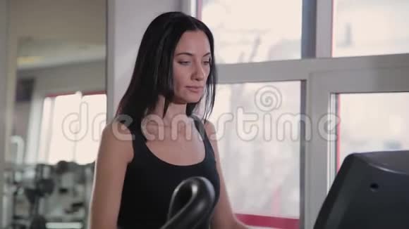 漂亮的运动年轻女孩在健身房训练椭圆教练视频的预览图