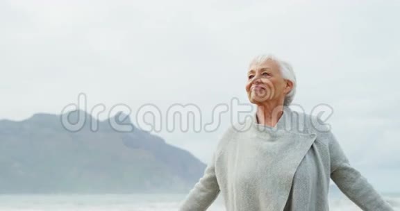 站在沙滩上举起双手的老妇人视频的预览图