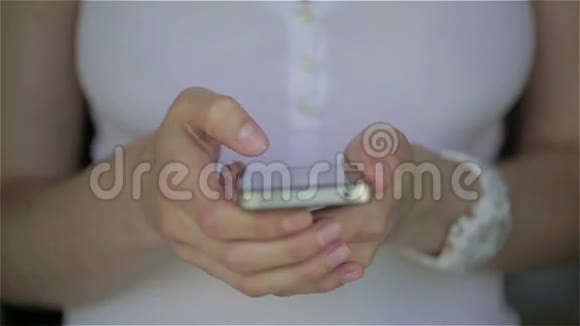 合上年轻女子白色连衣裙手指在智能手机上打字视频的预览图