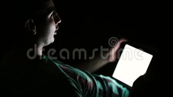 年轻人在黑暗中使用数码平板电脑视频的预览图