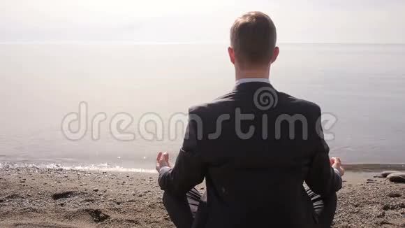 穿西装的商人坐在沙滩上沉思视频的预览图