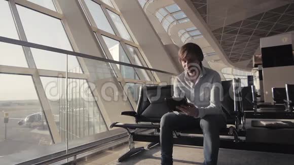 商人在机场使用平板电脑一个带背包的男性旅行者的轮廓商务和旅行视频的预览图