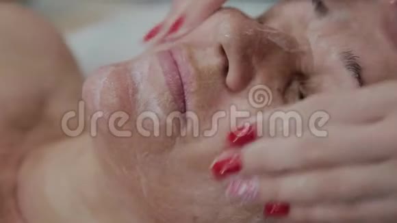 女性美容医生在美容诊所为老年妇女做面部按摩视频的预览图