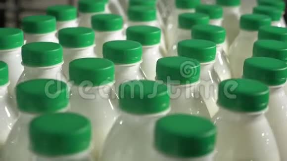 瓶子里的牛奶在传送带上移动牛奶厂传送带上有绿色帽子的牛奶视频的预览图