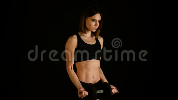 运动的年轻女性在黑色背景下做健身锻炼有魅力的健身女孩用哑铃来增加肌肉视频的预览图