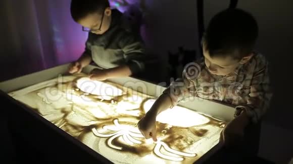 孩子们用手在沙子上画着光视频的预览图