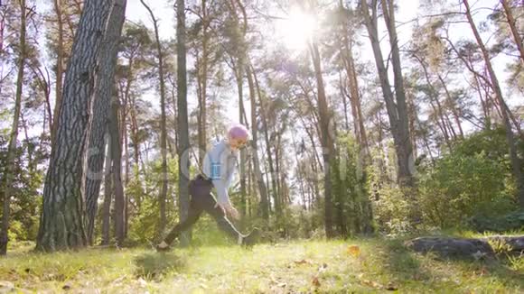 粉发在森林中伸展的年轻女士视频的预览图