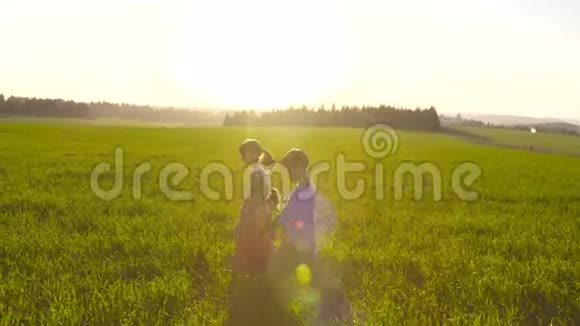 日落时分三个孩子在绿茵场上散步视频的预览图