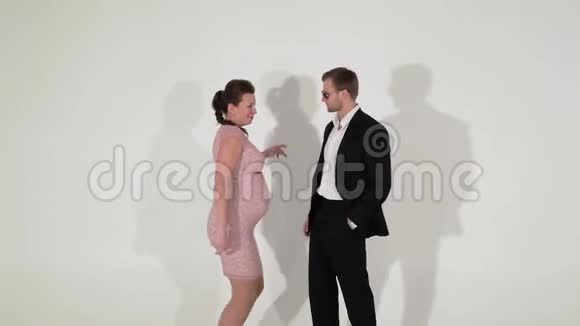 穿着黑色西装穿着白色衬衫的男人和孕妇正在灯光室跳舞视频的预览图