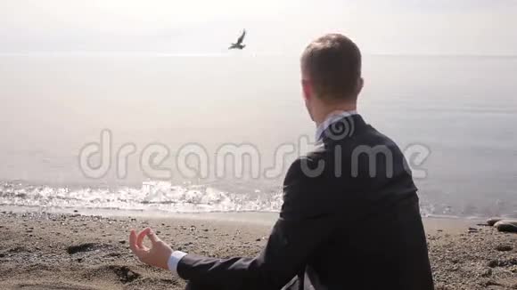 穿西装的商人坐在沙滩上沉思视频的预览图