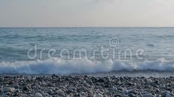 带有泡沫的大透明波海卵石滩五颜六色的石头视频的预览图