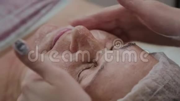 女性美容医生在美容诊所为老年妇女做面部按摩视频的预览图