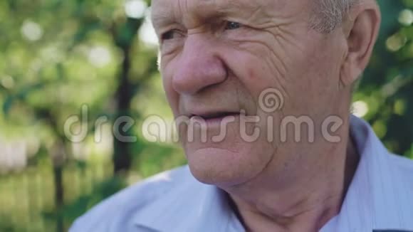 孤独老人在花园里对着镜头微笑的肖像4K视频的预览图
