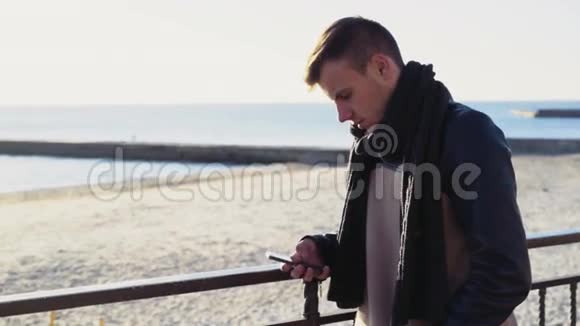 在秋天海滩上用智能手机的年轻人视频的预览图