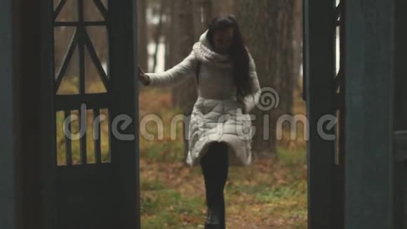 一个年轻的女人肩上背着一个背包在秋天的一个破旧的城市里散步视频的预览图