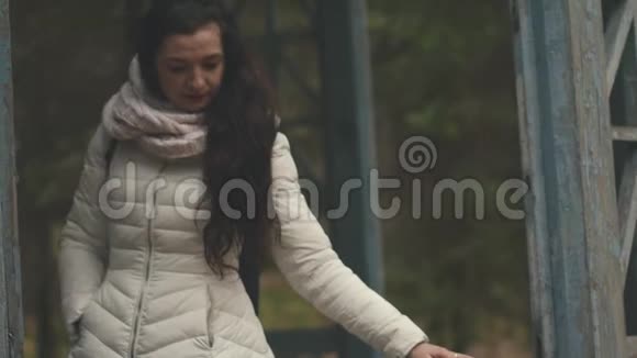一个年轻的女人肩上背着一个背包在秋天的一个破旧的城市里散步视频的预览图