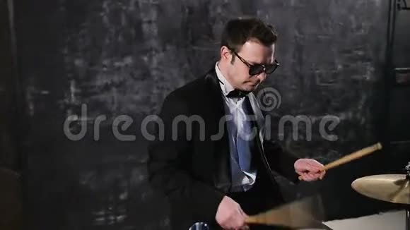 穿着黑色西装和太阳镜的人在鼓上玩耍摇滚乐队与鼓手上台表演视频的预览图