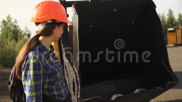 一位年轻的女工站在一台大铲挖掘机旁视频的预览图