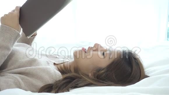 生活方式快乐的年轻亚洲女人躺在床上看书在家里穿着休闲服装视频的预览图