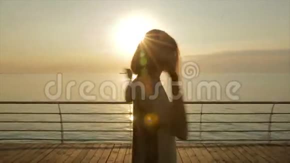 美丽的年轻女子在日落或日出时从船坞或码头跳舞视频的预览图