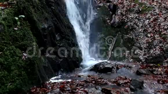 雨后水满的小瀑布对湿玄武岩巨石的反射充满溪流和气泡的乳白色的水视频的预览图