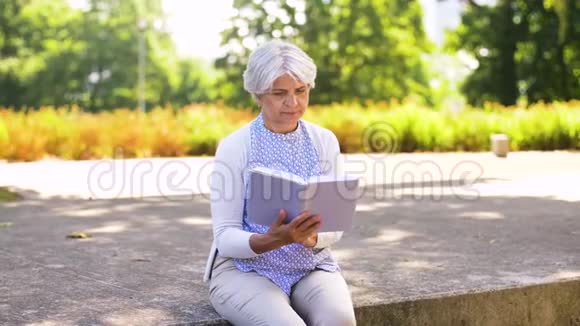 老年妇女读夏季公园的书视频的预览图
