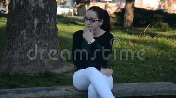 坐在城市公园长椅上的年轻女子视频的预览图