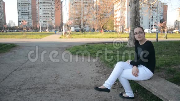 坐在城市公园长椅上的年轻女子视频的预览图