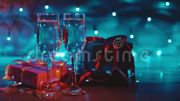 圣诞节和新年赠送两杯香槟蓝色花环背景视频的预览图