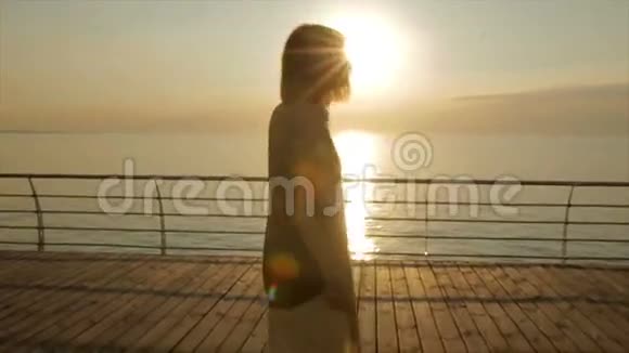 美丽的年轻女子在日落或日出时从船坞或码头跳舞视频的预览图